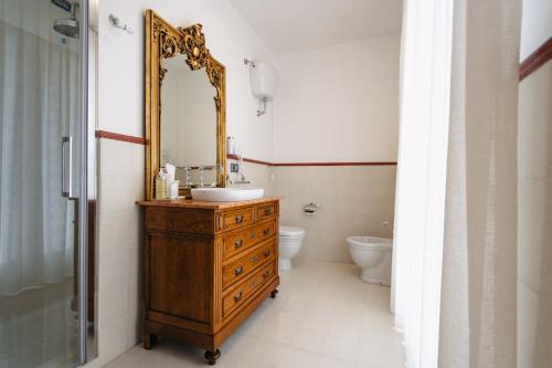 a bathroom with a sink and a mirror and a toilet at Villa Eleonora Paestum in Paestum