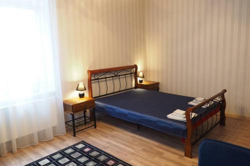 a bedroom with a bed and two tables and a window at In the heart of Kaunas in Kaunas