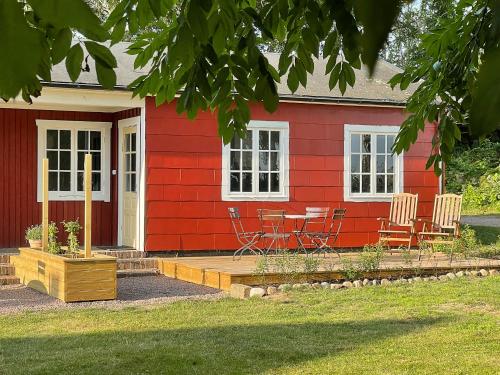 a red house with chairs and a table in front of it at Magnarp Strandbad in Vejbystrand