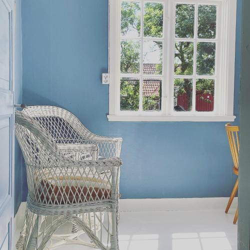 a blue room with a wicker chair and a window at Magnarp Strandbad in Vejbystrand