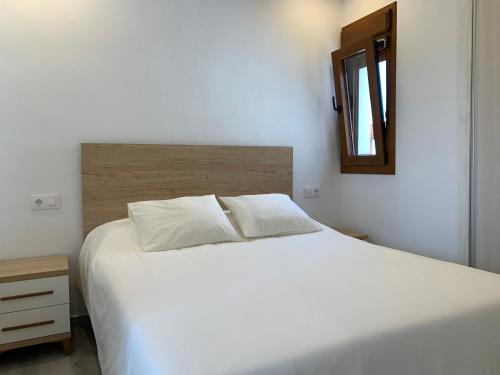 a bedroom with a white bed and a mirror at Apartamentos Villa Pirata Tarifa in Tarifa