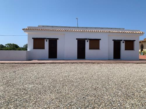 a white house with black doors and a gravel driveway at Apartamentos Villa Pirata Tarifa in Tarifa