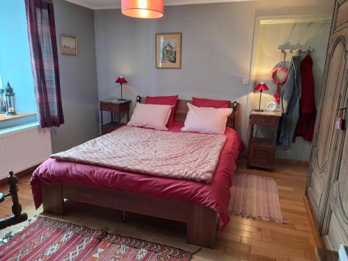 a bedroom with a bed with red sheets and pink pillows at LA CLOSERIE in Bouillon