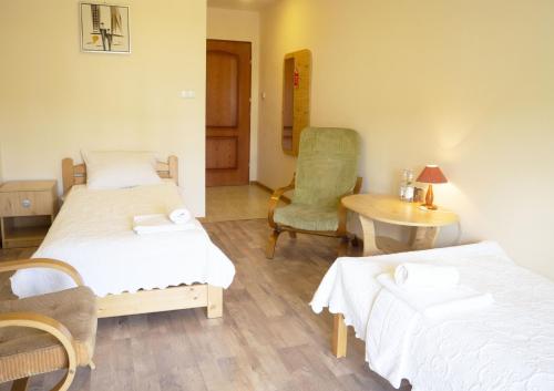 a room with two beds and a chair and a table at Zajazd Beskidy in Żywiec