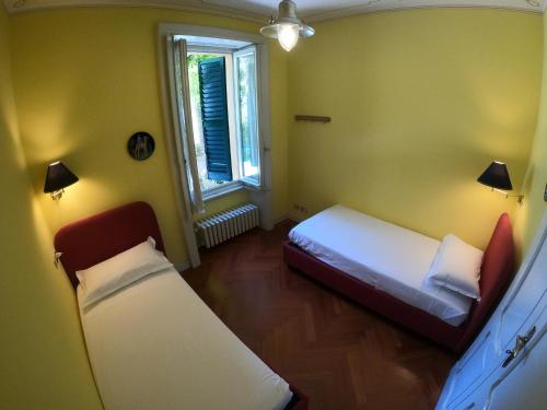 Cette petite chambre comprend 2 lits et une fenêtre. dans l'établissement Villa Reginella, à Varenna