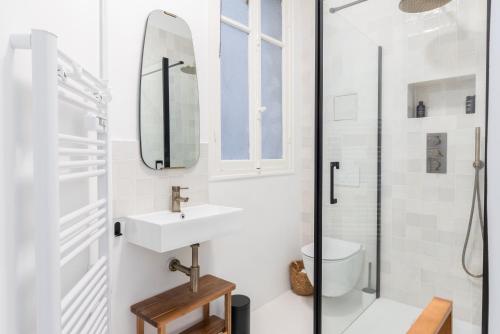 une salle de bain blanche avec un lavabo et un miroir dans l'établissement Ker Riviera, à Nice