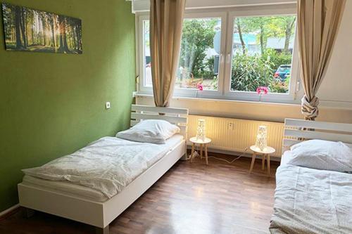 Habitación verde con 2 camas y ventana en Workers Apartment Bergisch Gladbach Bensberg, en Bergisch Gladbach
