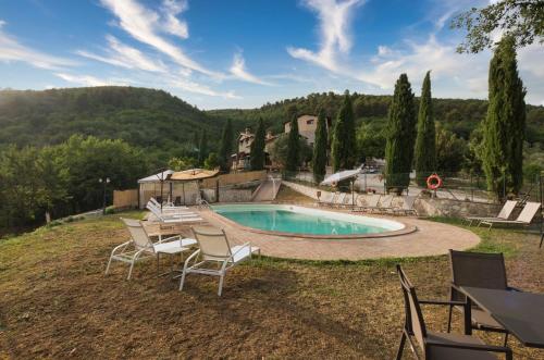 a swimming pool in a yard with chairs and a house at Borgo Incantato Spoleto in Pompagnano