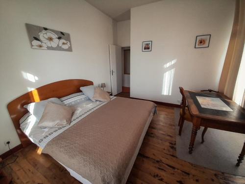a bedroom with a bed and a table and a desk at VILLA BONVOULOIR in Bagnères-de-Bigorre
