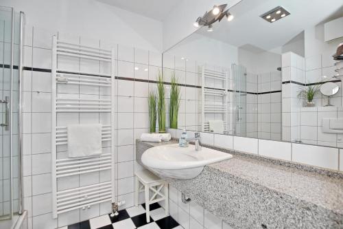 ein weißes Badezimmer mit einem Waschbecken und einem Spiegel in der Unterkunft Meeresblick Wohnung 104 - 4 Sterne DTV in Kühlungsborn