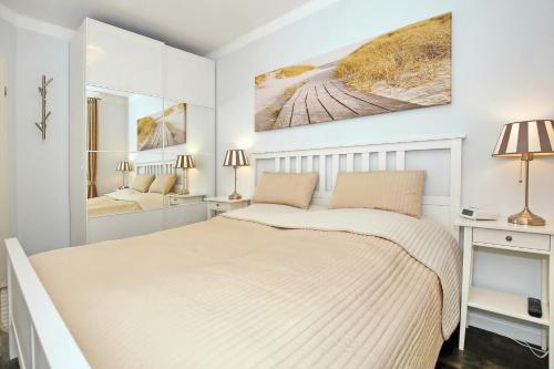 ein weißes Schlafzimmer mit einem Bett und einem Spiegel in der Unterkunft Meeresblick Wohnung 104 - 4 Sterne DTV in Kühlungsborn