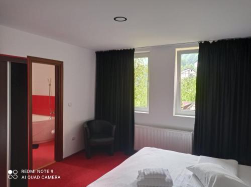 a bedroom with a bed and a window and a chair at Pensiunea Lucy in Sinaia
