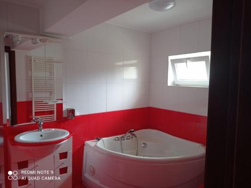 a red and white bathroom with a tub and a sink at Pensiunea Lucy in Sinaia