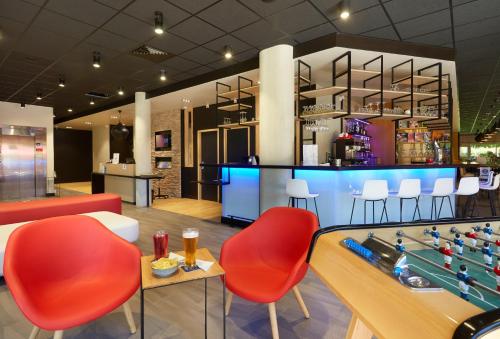 a restaurant with a pool table and red chairs at ibis Archamps Porte de Genève in Archamps
