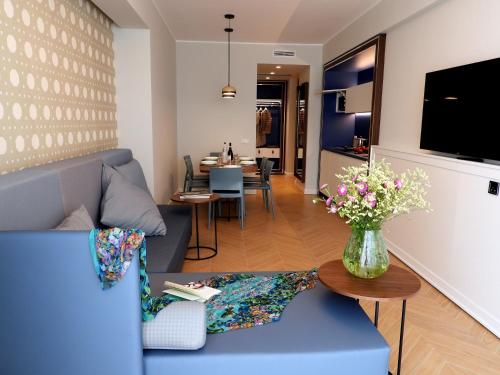 una sala de estar con un sofá azul y un jarrón de flores en BeSUITE Apartments, en San Benedetto del Tronto