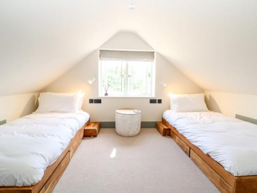 two beds in a attic room with a window at 12 Manor Farm Close in Kingham