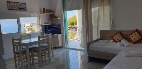 Un dormitorio con una cama y una mesa y un balcón. en Redsun Apartment, en Vlorë