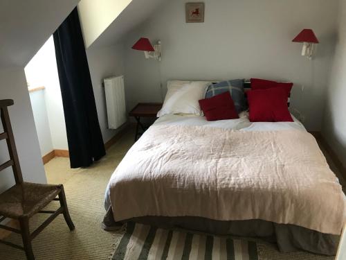 Un dormitorio con una cama con almohadas rojas y una silla en LocMajan, en Plouguin