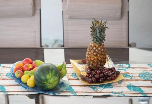 two plates of fruit on a table with a pineapple at Stavroula's Paradise House in Sikia