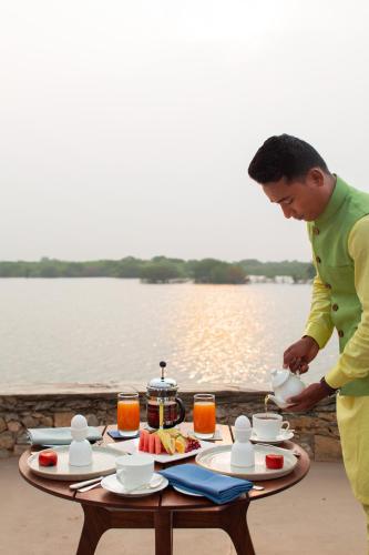 a man preparing food on a table next to a lake at RAAS Chhatrasagar, Nimaj, District Pali in Pāli