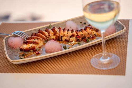 a plate of food next to a glass of wine at Hotel Agaró in Chipiona