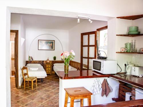 Casa Rural Alba Montis في غويخار سييرا: مطبخ وغرفة معيشة مع طاولة مع الزهور على المنضدة