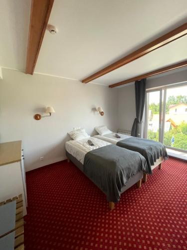 two beds in a room with a red carpet at Plytų 9 in Palanga