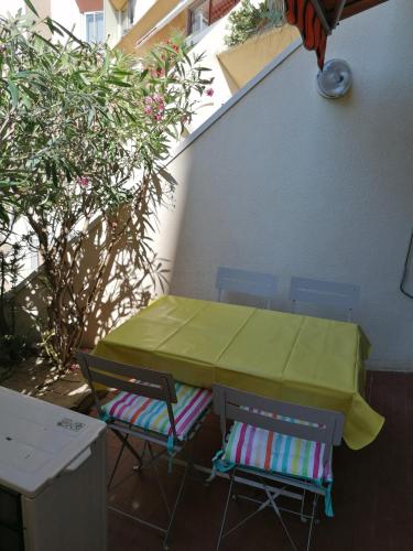 - une table et deux chaises avec une couverture verte sur la terrasse dans l'établissement Charmant studio Residence Carnon plage-Climatisation-Parking Prive, à Carnon-Plage
