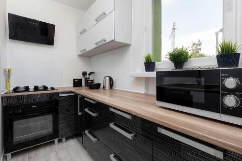 a kitchen with a black microwave and a wooden counter at Przymorze Apartment Jagiellońska by Renters in Gdańsk