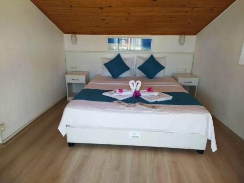 a bedroom with a bed with two flip flops on it at Alya Hotel Göcek in Göcek