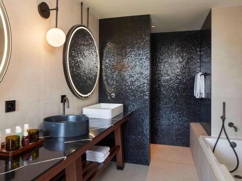 a bathroom with a large mirror and a sink at L'Esquisse Hotel & Spa Colmar - Mgallery in Colmar