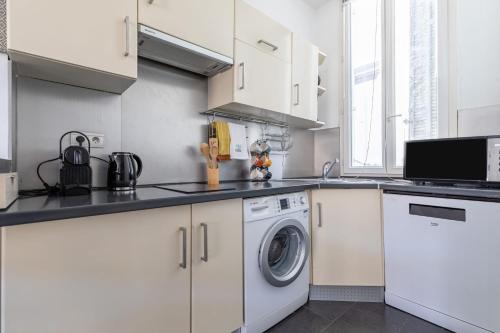 une cuisine avec des armoires blanches et une laveuse et une sécheuse dans l'établissement Charming Apartment In The Center Of Cannes, à Cannes