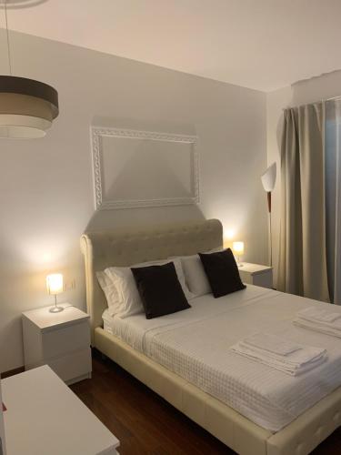 una camera con un letto bianco con due cuscini di L'alloro room's affittacamere a Pachino