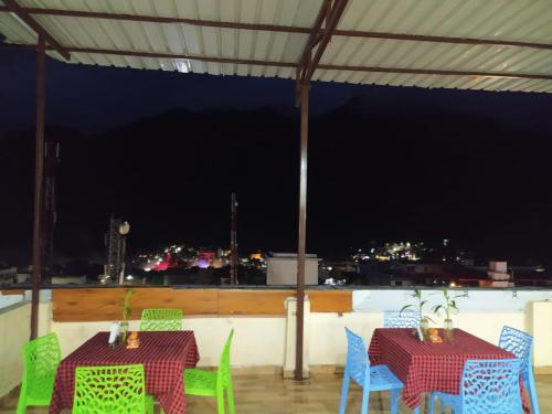 two tables and chairs on a balcony at night at Hotel The Shivaay - Delight Inn Rishikesh in Rishīkesh