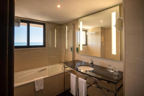 a bathroom with a sink and a tub and a mirror at Vila Gale Cascais in Cascais