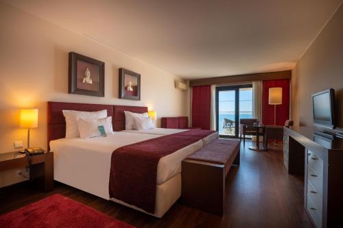 a hotel room with a large bed and a television at Vila Gale Cascais in Cascais
