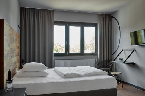a bedroom with a white bed and a window at Kröger by Underdog Hotels in Hamburg
