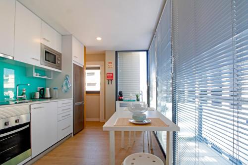 a kitchen with a table and a window with blinds at Casa São Vicente - Apartment Near City Centre with Private Parking in Viana do Castelo