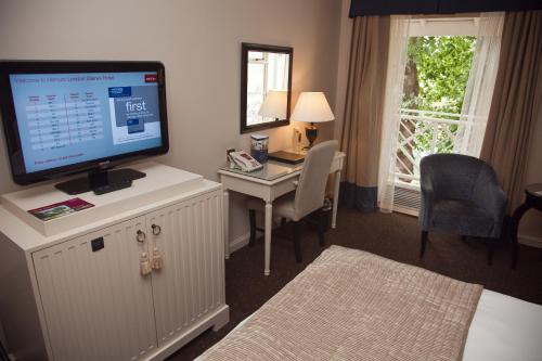 a hotel room with a desk with a computer and a monitor at Mercure London Staines-upon-Thames Hotel in Staines