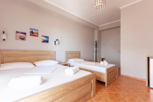 two beds in a room with white walls at Toni Retzo Rooms in Himare
