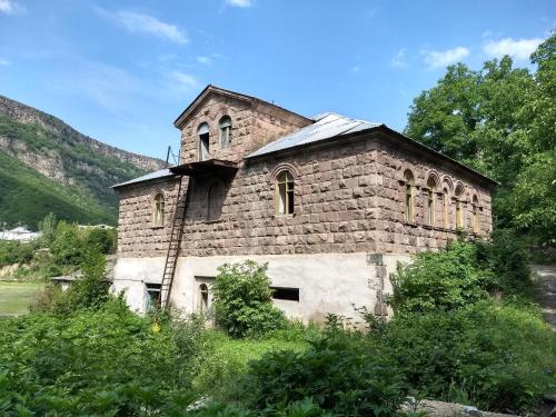 un viejo edificio de ladrillo con una torre de reloj. en Tumanyan Bathhouse Hostel, en Tʼumanyan
