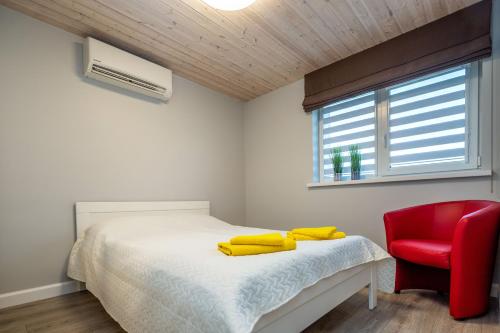 a bedroom with a bed and a red chair at Vila „Neptūnas“ in Palanga