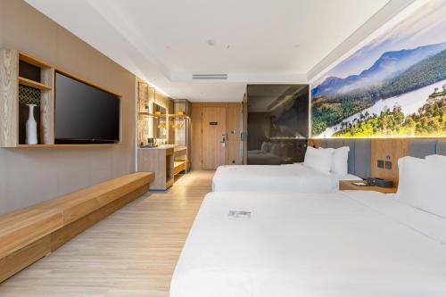 a hotel room with two beds and a flat screen tv at TRUE Go hotel in Chengdu