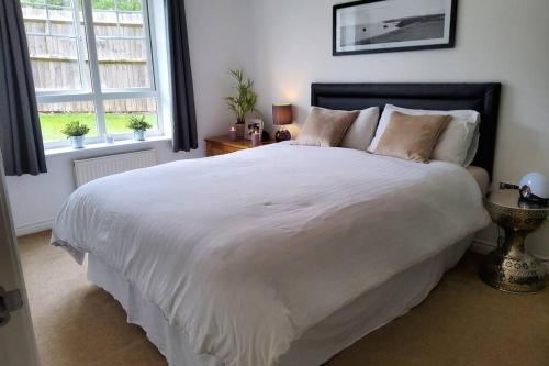 a bedroom with a large white bed with two windows at Stylish 2 bed 2 bathroom apartment for up to 5 in Warwick