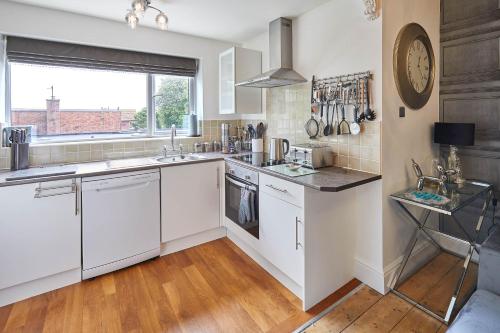una cucina con armadi bianchi e una grande finestra di Host & Stay - Apartment 2, 15 Prospect Hill a Whitby