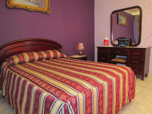 Hotel Lisboa في مدينة باناما: غرفة نوم بسرير وبطانية مقلمة ومرآة