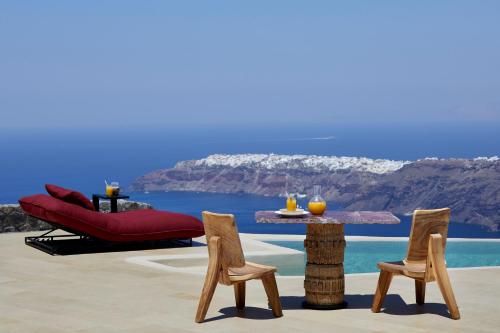 a table and chairs with a view of the ocean at White Pearl Cavalieri in Imerovigli