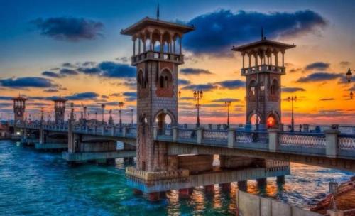 a pier with two towers in the water at sunset at Luxury apartment Alexandria in Alexandria