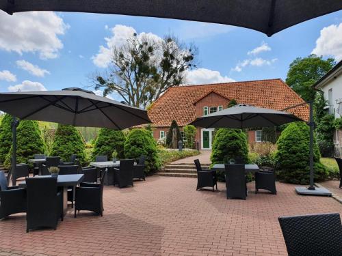 a patio with tables and umbrellas in front of a house at Van der Valk Golfhotel Serrahn - Adult Only in Serrahn