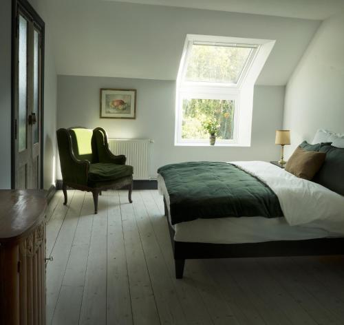 une chambre avec un lit, une chaise et une fenêtre dans l'établissement The Riverhouse, magical house with garden by the river Seine, à Gyé-sur-Seine